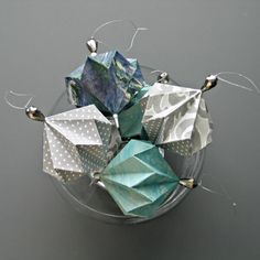 an origami sculpture is displayed on a glass plate with silver pins and polka dots