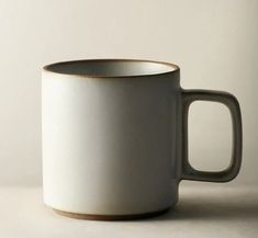 a white and brown coffee cup sitting on top of a table