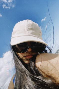 a woman with long hair wearing sunglasses and a hat