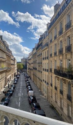 an aerial view of a street with cars parked on both sides and buildings in the background