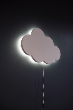 a white cloud shaped light on top of a black wall