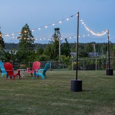 several lawn chairs are sitting in the middle of a yard with string lights strung over it