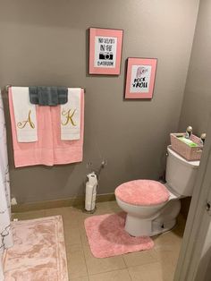 a bathroom with pink rugs and pictures on the wall above the toilet, along with other accessories