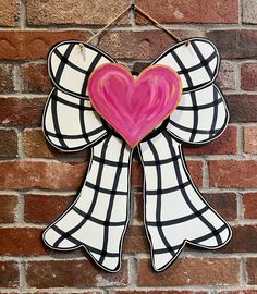 a heart shaped decoration hanging on a brick wall next to a brick wall with a black and white checkerboard pattern