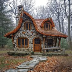 a small house made out of rocks and wood in the woods with leaves on the ground