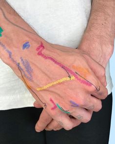 a man holding his hands with colored crayons all over it's body