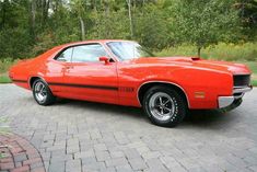 an orange muscle car parked in a driveway