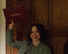 a woman is holding up a book in front of her face and smiling at the camera