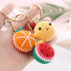 a hand holding two small crocheted fruit key chains