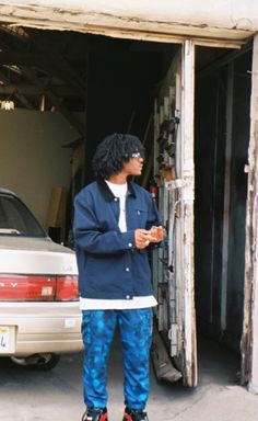 a man standing in front of a garage door with his hands on his hips and looking at something