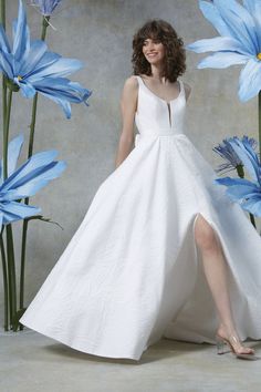 a woman in a white dress standing next to blue flowers