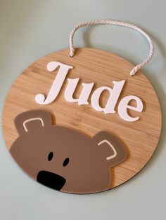 a wooden sign that says jude with a brown bear face on it's side