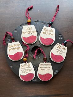 six wine tags with sayings on them sitting on top of a metal pan covered in red string