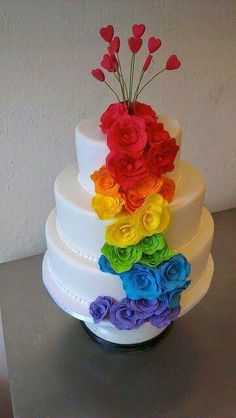 a multi - tiered wedding cake with rainbow flowers on the top and bottom layer