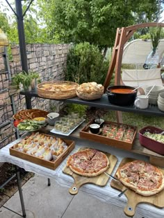 an outdoor buffet with pizzas and other foods