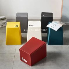 four different colored stools sitting on top of a tile floor next to each other