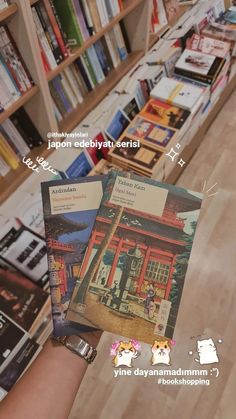 a person holding up a book in front of a bookshelf filled with books