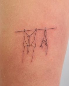 a line drawing on the back of a woman's thigh shows two clothes hanging from a rope