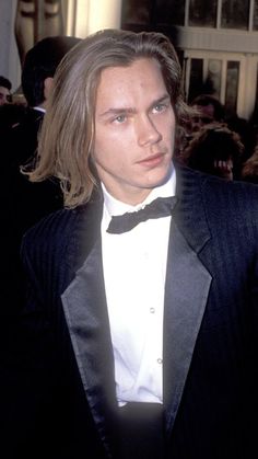 a young man in a tuxedo and bow tie standing next to an audience