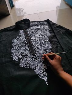 someone is painting on a black shirt with white designs