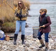 two women standing on rocks with fishing rods