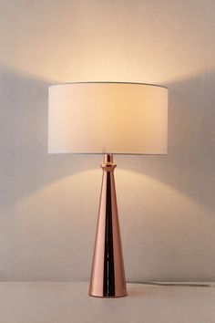 a table lamp with a white shade on it's base and a light bulb in the shape of a cone