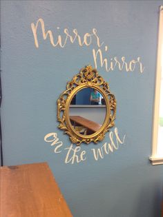 a mirror on the wall with writing written on it and a wooden table next to it