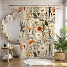 a bathroom with a flower shower curtain next to a potted plant on the floor