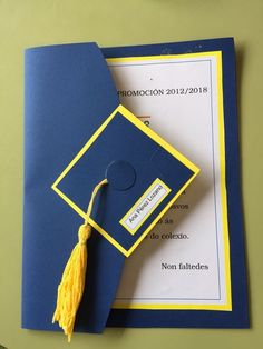 a blue and yellow graduation cap with a tassel on it's end sitting on top of a piece of paper