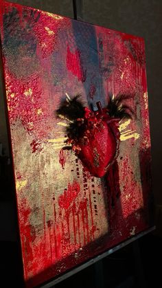 a painting with red and gold paint on it that has a heart in the middle