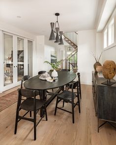 a dining room table and chairs in front of an open staircase leading up to the second floor