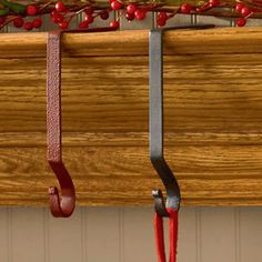 a pair of scissors hanging from a window sill with red berries on the top