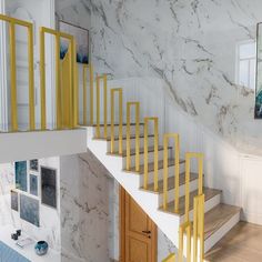 a room with marble walls and yellow railings on the stair case next to an open door