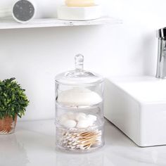 a bathroom counter with various items on it and a potted plant in the corner