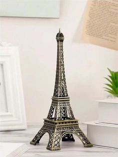 the miniature eiffel tower is on display in front of a white table with a potted plant