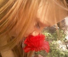 a close up of a person holding a flower in front of her face and looking down at it