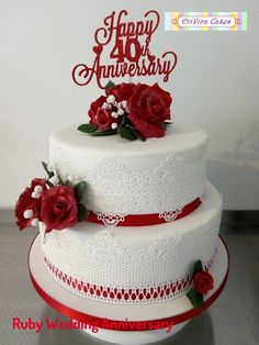 a three tiered cake with red roses on top and the words happy anniversary written on it