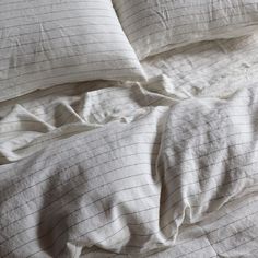 an unmade bed with white sheets and pillows