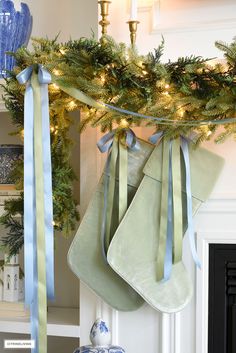 christmas stockings hanging from a mantel decorated with blue and green ribbon