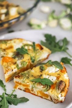 two slices of quiche on a plate with parsley sprigs next to it