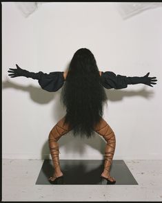 a woman with long black hair standing on one leg