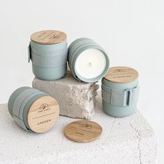 three wooden containers and one candle are sitting on a rock with two smaller ones next to it