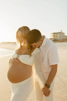 a pregnant woman standing next to a man on the beach