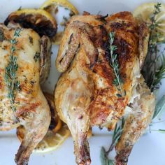 two pieces of chicken with herbs and lemons