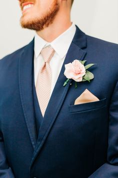 a man in a blue suit with a pink flower on his lapel and white shirt