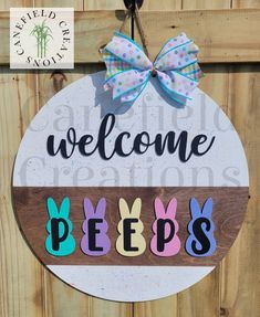 a welcome sign hanging on the side of a wooden fence with an easter bunny decoration