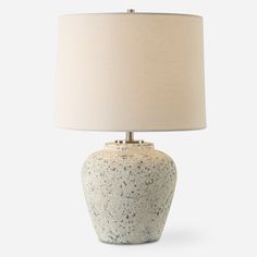 a table lamp with a white base and a light beige shade on the top of it