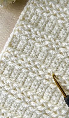 a crocheted white blanket next to a pair of scissors