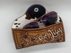 a pair of sunglasses sitting on top of a wooden case with cow print and flowers