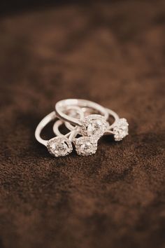 three diamond rings sitting on top of a brown velvet covered surface in sepia tone